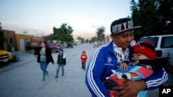 IIn this July 10, 2019, photo, Juan Carlos Perla carries his youngest son, Joshua Mateo Perla, as the family leaves their home in Tijuana, Mexico, for an asylum hearing in San Diego. 
