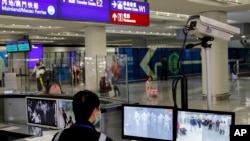 FILE - A health surveillance officer monitors passengers arriving at the Hong Kong International airport in Hong Kong, Jan. 4, 2020. 