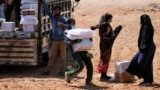 (FILE) A worker holds bags and a box of humanitarian aid in the opposition-held Idlib, Syria June 9, 2021.