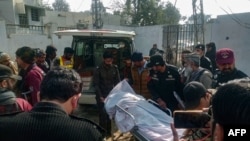 Police officers move the body of a colleague who was killed in an attack on a police station, at a hospital in Dera Ismail Khan, Pakistan, on Feb. 5, 2024.