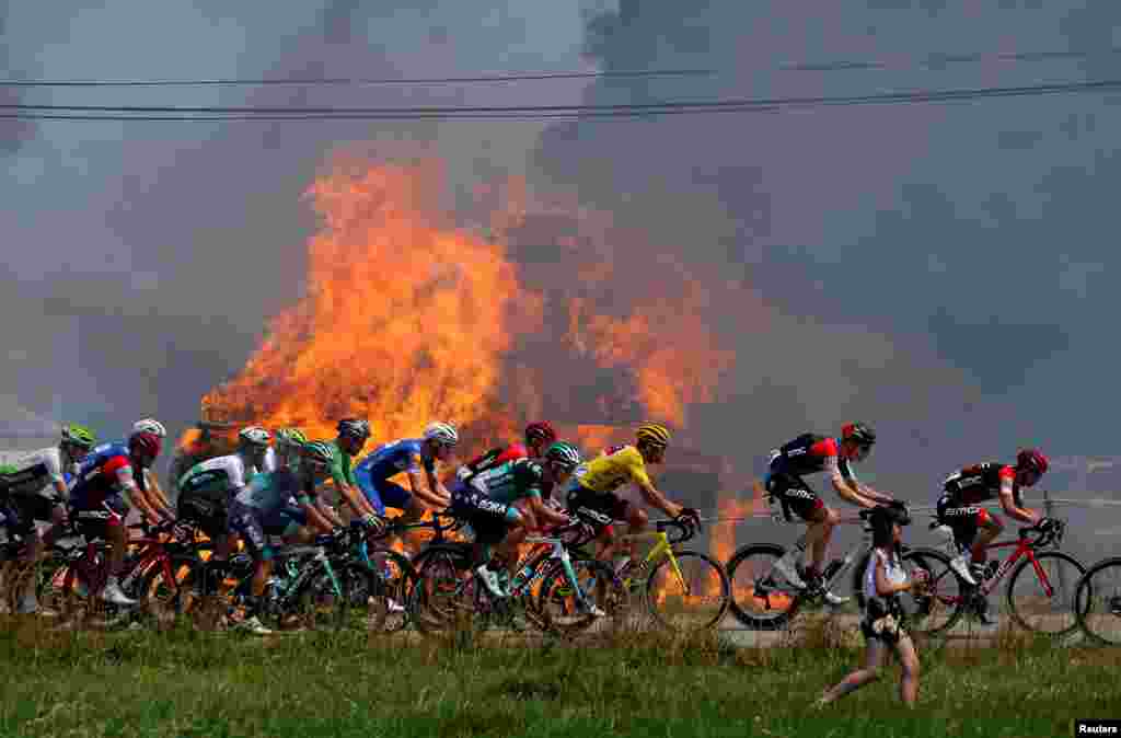 The peloton passes hay bales on fire during the Tour de France 181-km Stage 6 from Brest to Mur-de-Bretagne Guerleden.