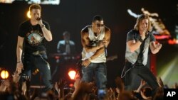 Nelly, center, and Brian Kelley, left, and Tyler Hubbard, of musical group Florida Georgia Line, perform at ACM Presents: Tim McGraw's Superstar Summer Night at the MGM Grand Garden Arena, April 8, 2013, in Las Vegas.