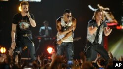 Nelly, center, and Brian Kelley, left, and Tyler Hubbard, of musical group Florida Georgia Line, perform at ACM Presents: Tim McGraw's Superstar Summer Night at the MGM Grand Garden Arena, April 8, 2013, in Las Vegas.