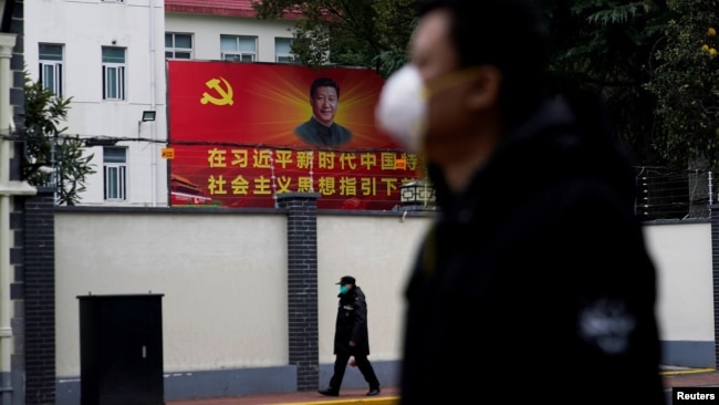 戴着口罩的行人走过上海街头习近平的画像。(2020年2月10日)