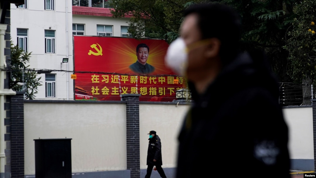 戴著口罩的行人走過上海街頭習近平的畫像。（2020年2月10日）