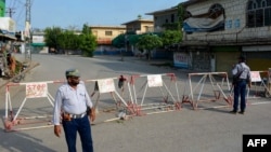 Policemen stand guard along a barricaded street near an army cantonment, a day after it was attacked by a militant suicide squad in Bannu, northwestern Pakistan, July 16, 2024.