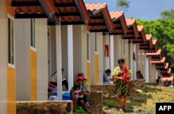 Indigenous Gunas sit outside their new homes in Nuevo Carti, Panama, on May 29, 2024. Panamanian authorities handed over the keys to their new homes on the mainland to some 300 families from Gardi Sugdub, a small Caribbean island affected by rising sea levels.