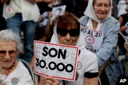 FILE - Mothers of "Plaza de Mayo" member Tati Almeida holds a sign that reads in Spanish "They are 30,000," referring to those killed by the Argentine dictatorship, as she listens to the verdicts for the accused in a human rights trial, Nov. 29, 2017.