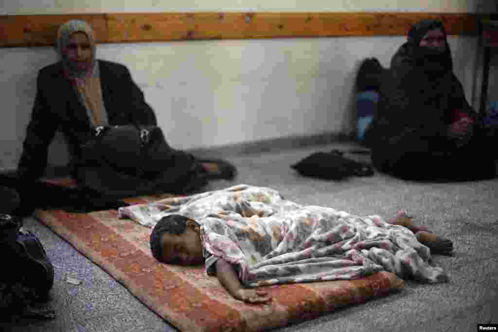 A Palestinian boy, who fled his house with his family following an Israeli ground offensive, sleeps as he stays at a United Nations-run school in Rafah, in the southern Gaza Strip, July 18, 2014.