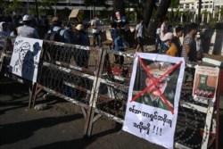 A poster featuring army chief Senior General Min Aung Hlaing is displayed on a barricade as protesters take part in a demonstration against the military coup in front of the Central Bank of Myanmar in Yangon, Feb. 11, 2021.