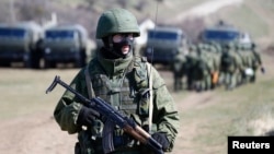 FILE - An armed man, believed to be a Russian soldier, stands guard outside a military base in Perevalne, near the Crimean city of Simferopol, March 21, 2014, during the days of Russia's annexation of Ukraine's Black Sea peninsula.