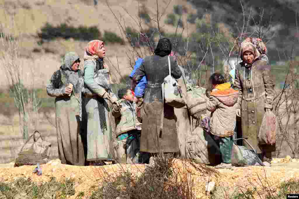 Internally displaced people, covered with mud, wait as they are stuck in the town of Khirbet Al-Joz, in Latakia countryside, waiting to get permission to cross into Turkey near the Syrian-Turkish border, Syria, Feb. 7, 2016.