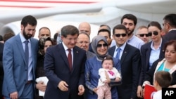 다부토울로 터키 총리가 앙카라 공항에서 풀려난 인질과 함께 서있다.