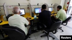 FILE - People surf the Internet at an Internet cafe in Baghdad, Nov. 11, 2012. 