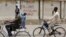 FILE - Two boys ride their bicycles past a sign reading "Stop killing Muslims Army" on a wall in Kano, Nigeria, April 8, 2016. 