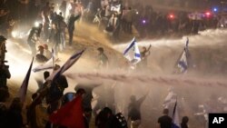 Israeli police use a water cannon to disperse demonstrators blocking a highway during a protest against plans by Prime Minister Benjamin Netanyahu's government to overhaul the judicial system, in Tel Aviv, Israel, March 27, 2023.