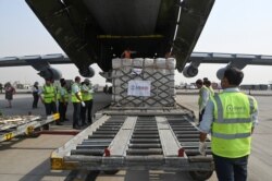 FILE - Ground staff unload COVID-19 relief supplies from the United States at the Indira Gandhi International Airport cargo terminal in New Delhi, India, Apr. 30, 2021.