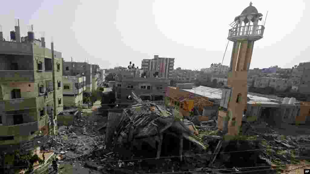 Palestinians walk around the ruins of the Al-Tawfeeq Mosque after it was hit by an overnight Israeli missile strike in the Nuseirat refugee camp, central Gaza Strip, July 12, 2014.