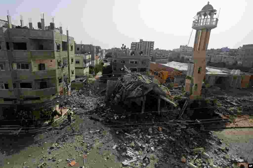 Palestinians walk around the ruins of the Al-Tawfeeq Mosque after it was hit by an overnight Israeli missile strike in the Nuseirat refugee camp, central Gaza Strip, July 12, 2014.