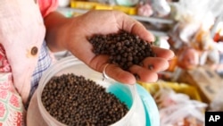 A vendor holds a handful of Kampot pepper before selling at a market in Phnom Penh, Cambodia, Tuesday, March 1, 2016.