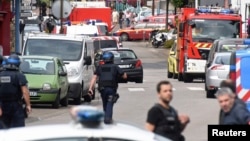 Police and rescue workers stand at the scene after two assailants had taken five people hostage in the church at Saint-Etienne-du -Rouvray near Rouen in Normandy, France, July 26, 2016. Two attackers killed a priest with a blade and seriously wounded anot