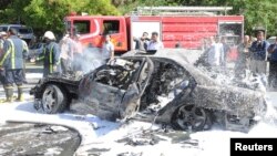 People stand near debris and a damaged vehicle after an explosion at al-Mezze neighbourhood in Damascus April 29, 2013, in this handout photograph distributed by Syria's national news agency SANA. Syrian Prime Minister Wael al-Halki survived the bomb atta