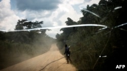 Un congolais marche sur la route reliant la ville de Bunia à celle de Mambasa, dans la province de l’Ituri, le 10 juillet 2018. John Wessels /AFP