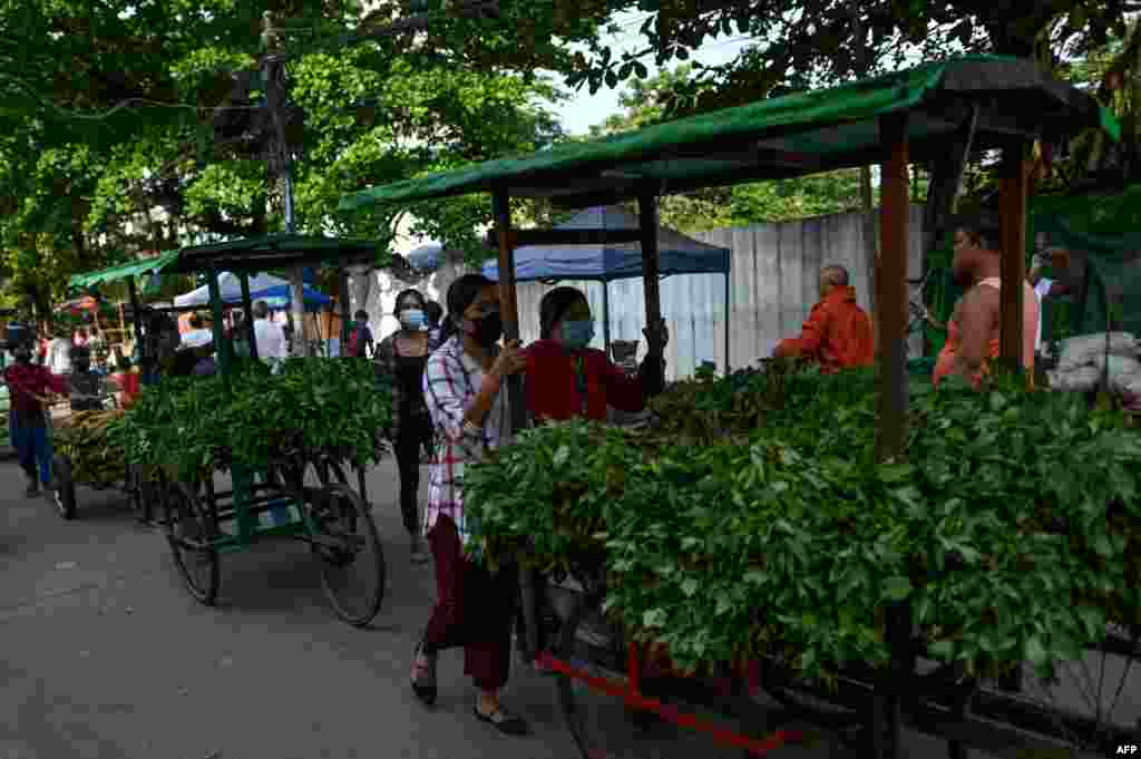People push carts with vegetables for distribution during a "Donate your extras, take what you need" - a donation drive aimed at helping low income households - in Thaketa township in Yangon as communities cope with an economic downturn in Myanmar.