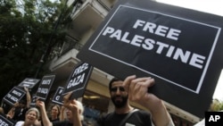 U.S. and French activists chant slogans as they hold placards after a news conference about an international flotilla to blockaded Gaza, in Athens, June 27, 2011