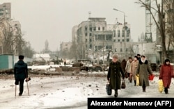 Pedestrians cross a one-legged man in February 1996 in the devastated streets of Grozny.