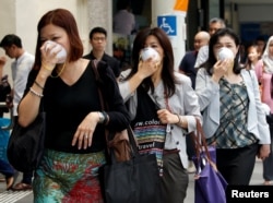 Women cover their faces with masks as haze shrouds Singapore's central business district, Aug. 26, 2016.