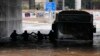 Passengers are silhouetted as they wade through high water after evacuating a bus stuck in a flooded underpass in southern Athens, Oct. 14, 2021. 