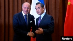 Menlu Perancis, Laurent Fabius (kiri) berjabat tangan dengan Menlu China Wang Yi sebelum memulai pertemuan di kantor Kemenlu China di Beijing (15/9).