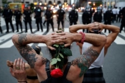Protesters kneel in front of New York City Police Department officers before being arrested for violating curfew beside the iconic Plaza Hotel on 59th Street, June 3, 2020, in New York.