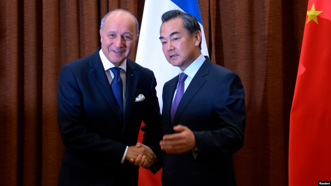 Menlu Perancis, Laurent Fabius (kiri) berjabat tangan dengan Menlu China Wang Yi sebelum memulai pertemuan di kantor Kemenlu China di Beijing (15/9).