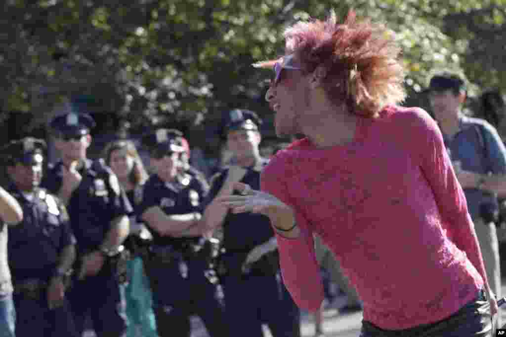 Police officers watch as an activist associated with the Occupy Wall Street movement performs during a gathering of the movement in Washington Square park, September 15, 2012.