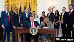 د امریکا ولسمشر او لومړۍ میرمن میلانیا ټرمپ د اجراییوي فرمان د لاسلیک کولو پر مهال 