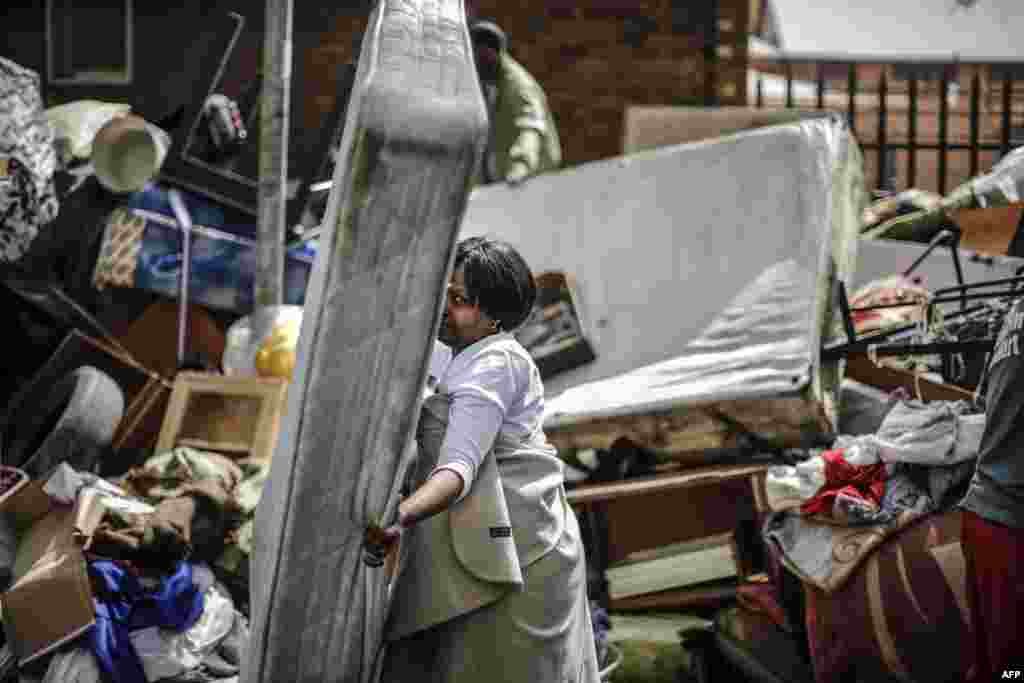 A woman salvages a mattress from a pile of furniture left in a street of the popular downtown district of Hillbrow, South Africa, following an eviction of an occupied building.