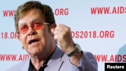 British musician Elton John raises his fist as he delivers a news conference at the 22nd International AIDS Conference (AIDS 2018), the largest HIV/AIDS-focused meeting in the world, in Amsterdam, Netherlands, July 24, 2018.