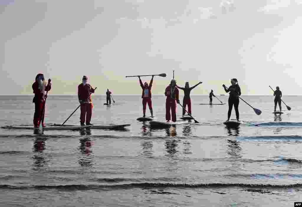 Members and friends of a Cypriot surfing club, dressed as Santa Claus to celebrate the holidays, set out to sea on stand up paddle (SUP) boards at Makenzy beach, in the southern city of Larnaca.