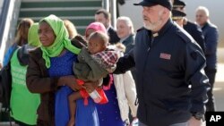 FILE - A woman and child are escorted by a police officer upon their arrival in Pratica di Mare's military airport, near Rome, Nov. 14, 2018. 