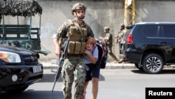 Seorang tentara membantu seorang siswa untuk menemui orang tuanya setelah baku tembak meletus di Beirut, Lebanon, pada 14 Oktober 2021. (Foto: Reuters/Mohamed Azakir)