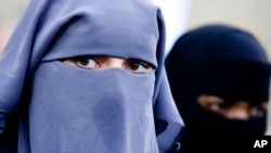 FILE - Unidentified women are seen wearing a niqab during a demonstration outside the Dutch parliament against a proposed ban on the burqa, in The Hague, Netherlands.