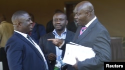 Roger Lumbala (R), a former member of parliament in the Democratic Republic of Congo who joined the M23 rebel group, chats with colleagues shortly after attending a peace talk meeting in Uganda's capital Kampala, January 11, 2013.