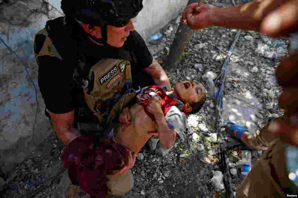 Iraqi soldiers from the 9th Armored Division give drops of water to a dehydrated child rescued earlier by soldiers at the frontline near the Old City in western Mosul.