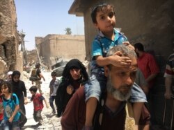 FILE - Iraqi civilians flee fighting against Islamic State militants in the Old City of Mosul, Iraq, July 1, 2017.