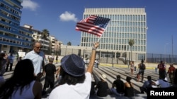 FILE - A woman waves a U.S flag in front of the U.S. Interests Section, in Havana, July 20, 2015.