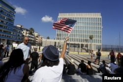 A woman waves a U.S flag in front of the U.S. Interests Section, in Havana, July 20, 2015.