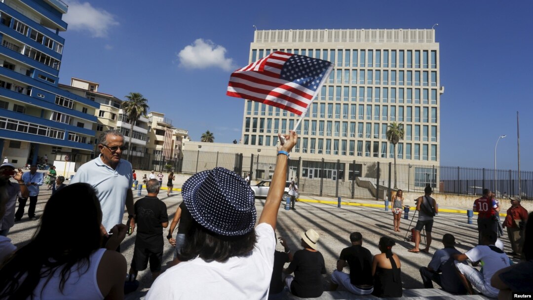 FILE - A woman waves a U.S flag in front of the U.S. Interests Section in Havana, July 20, 2015.