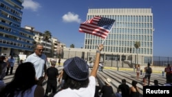 FILE - A woman waves a U.S flag in Havana, July 20, 2015.